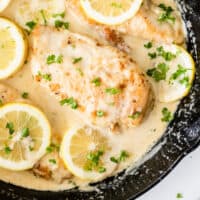 creamy lemon chicken breasts in a cast iron skillet with recipe name at the bottom