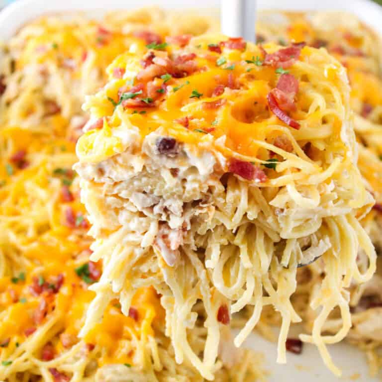 square image of a slice of Creamy Ranch Chicken Spaghetti Casserole on a spatula over the pan