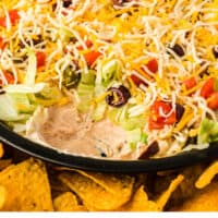 creamy taco dip with a bite taken out to show the layers with recipe name at the bottom