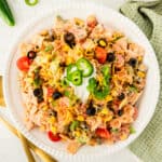 square image of creamy taco pasta salad topped with sour cream, cilantro, and jalapeno slices