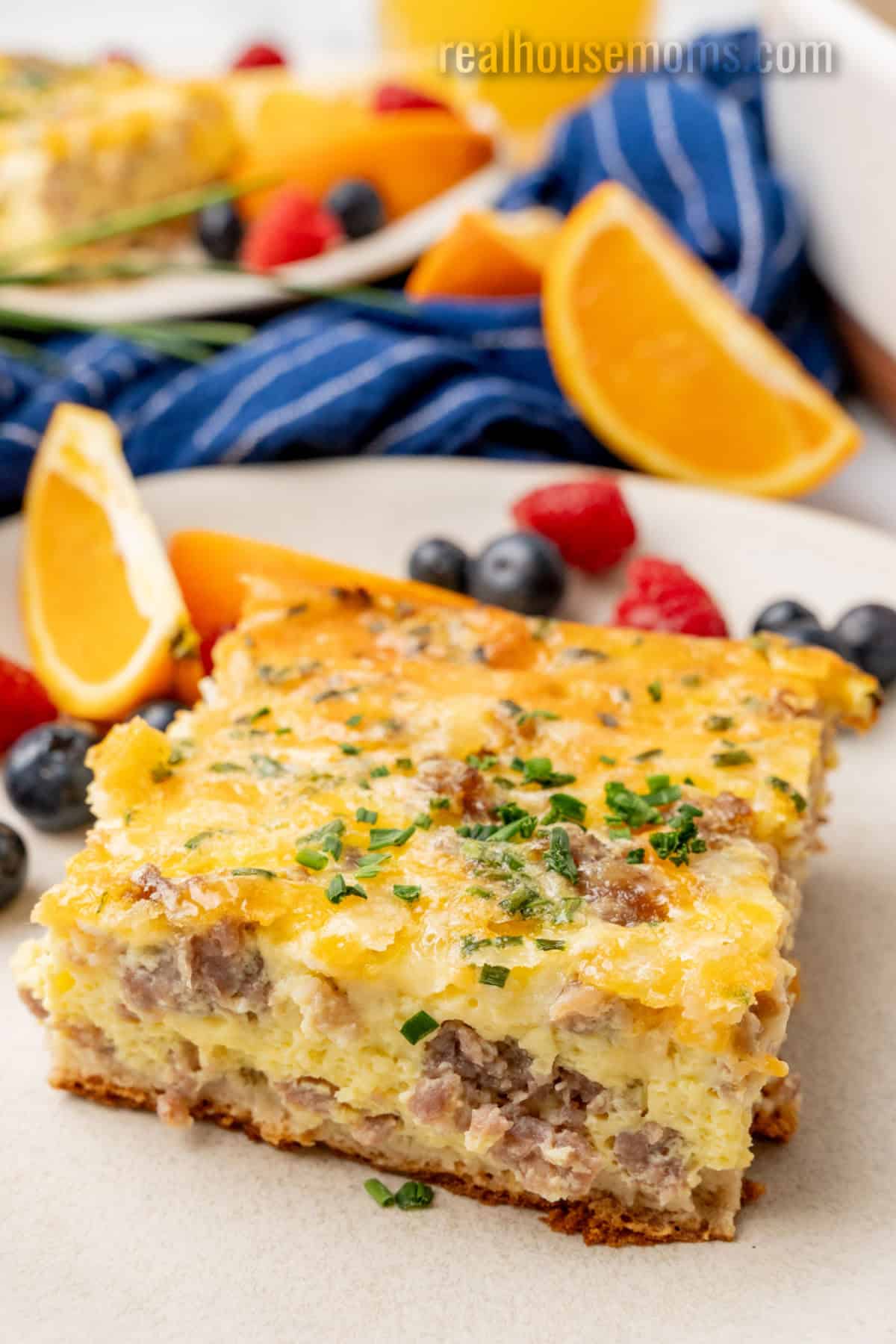 square of crescent roll breakfast casserole on a plate with fresh fruit