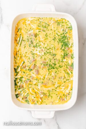 egg mixture poured over cheese and sausage in a baking dish