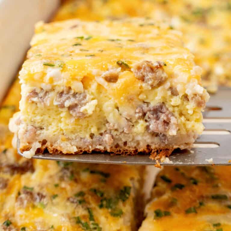 square image of a slice of crescent roll breakfast casserole on a metal spatula over the baking dish