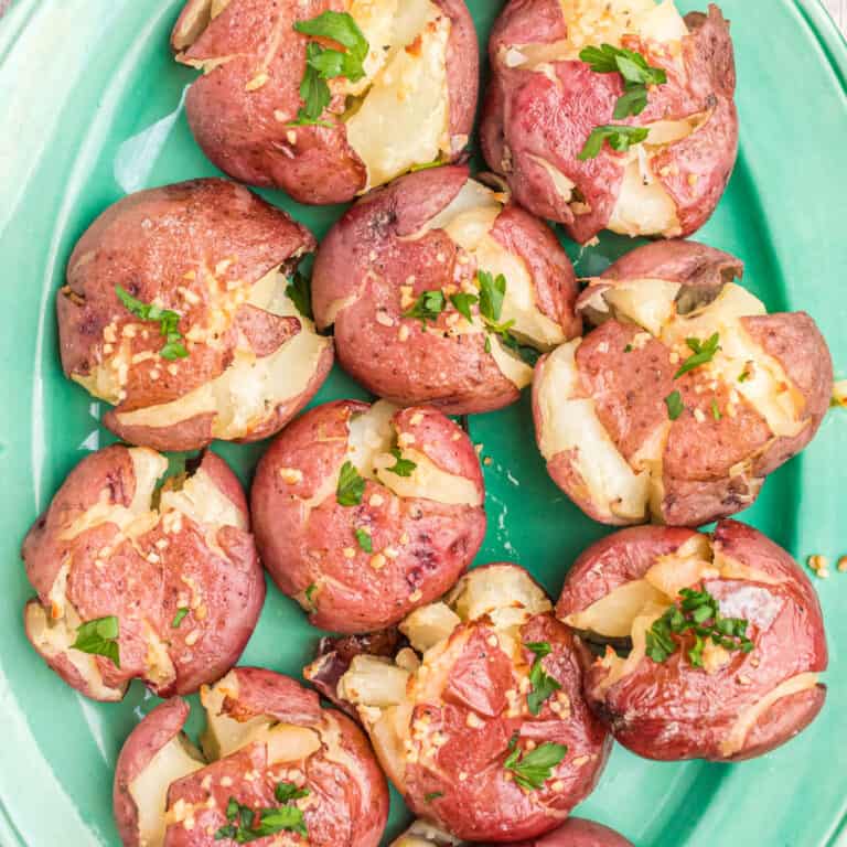 square image of crispy garlic smashed potatoes on a platter