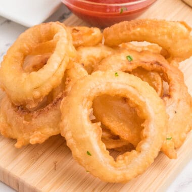 square image of a pile of onion rings on a wooden board