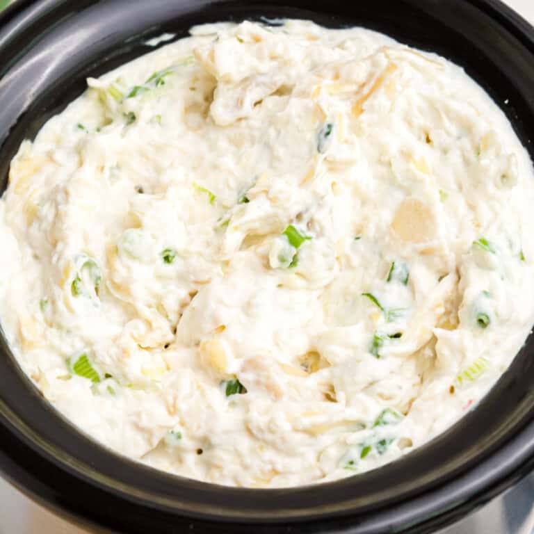 square image of artichoke crab dip in a crock pot