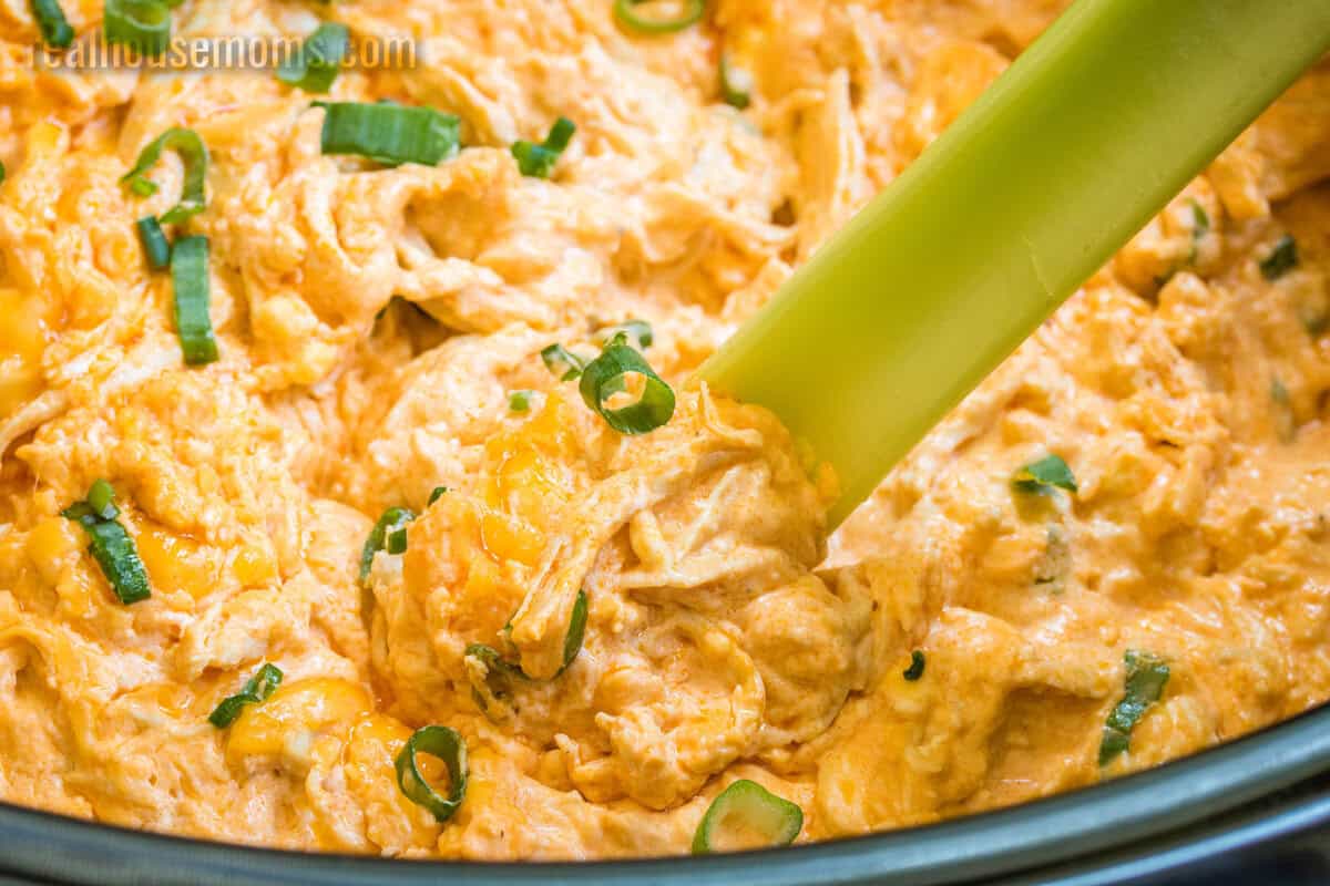 celery stick being dipped into crock pot buffalo chicken dip