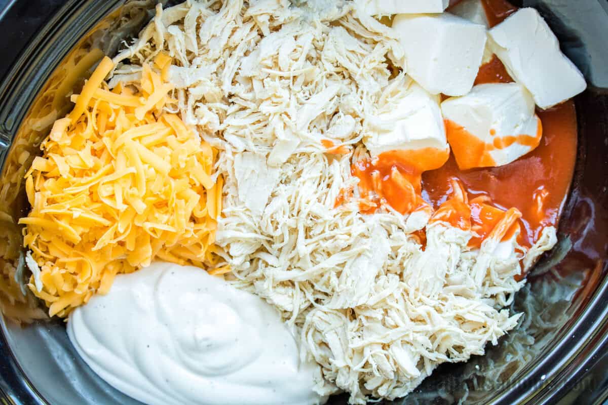 buffalo chicken dip ingredients in a black crockpot