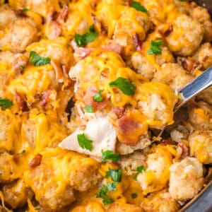 square image of a spoonful of crock pot cheesy chicken, bacon & tater tot bake over the slow cooker
