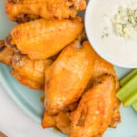 crock pot chicken wings on a plate with a bowl of blue cheese fip and veggies with recipe name at the bottom