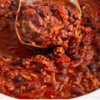 ladle of crock pot chili over the slow cooker with recipe name at the bottom