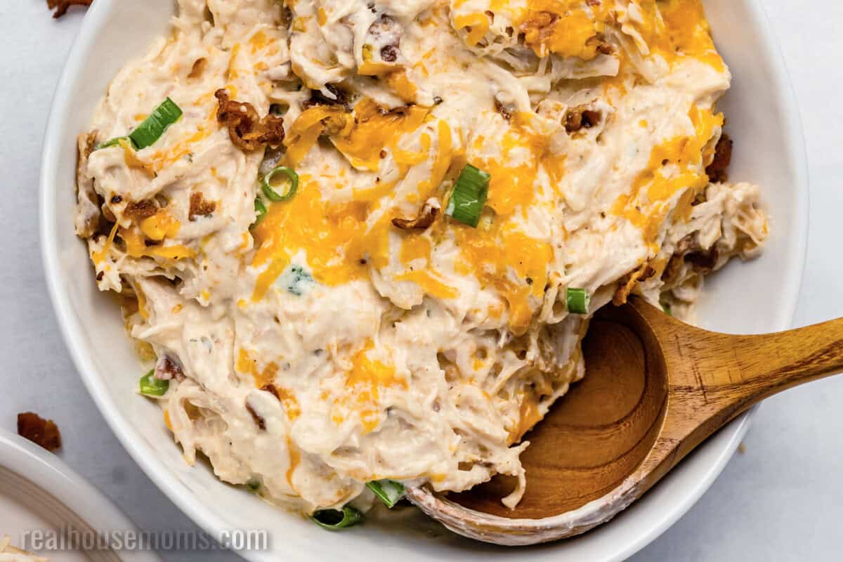 bowl of crockpot crack chicken with a wooden serving spoon