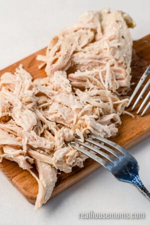 cooked ranch chicken breast shredded with forks on a cutting board