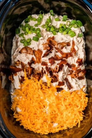 bacon, green onions, and cheddar cheese added to creamy ranch chicken in a slow cooker