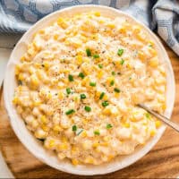 square image of crock pot creamed corn in a serving bowl with a spoon