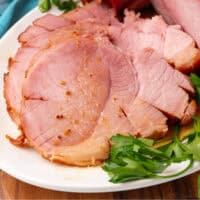 slice of crock pot ham on the platter next to the ham with recipe name at the bottom