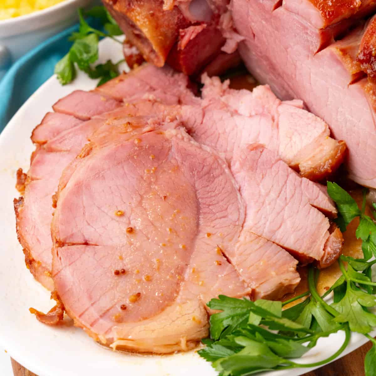 square image of crock pot ham slices on a platter next to the ham and some parsley