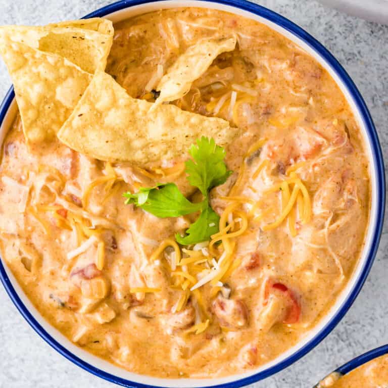 square image looking down at a bowl of crock pot king ranch chicken soup with garnishes