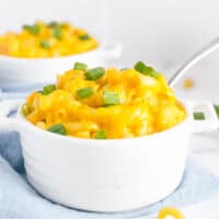 square image of mac and cheese in a bowl with a spoon and sliced green onions