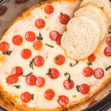 square image of crock pot pizza dip topped with pepperoni and basil with bread slices