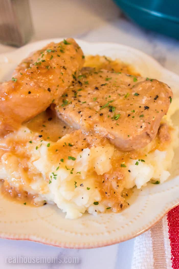 crock pot pork chops with gravy served over mashed potatoes on a dinner plate