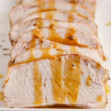 square image of crock pot pork loin cut into slices with pan sauce drizzled over top