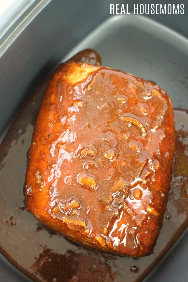 pork roast in a crock pot with orange sauce poured over the top