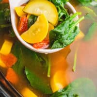 ladleful of crock pot vegetable soup over the slow cooker with recipe name at the bottom