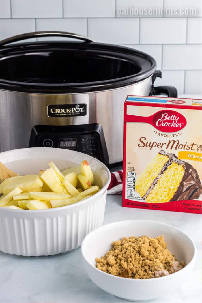 ingredients to make apple cobbler next to a crock pot