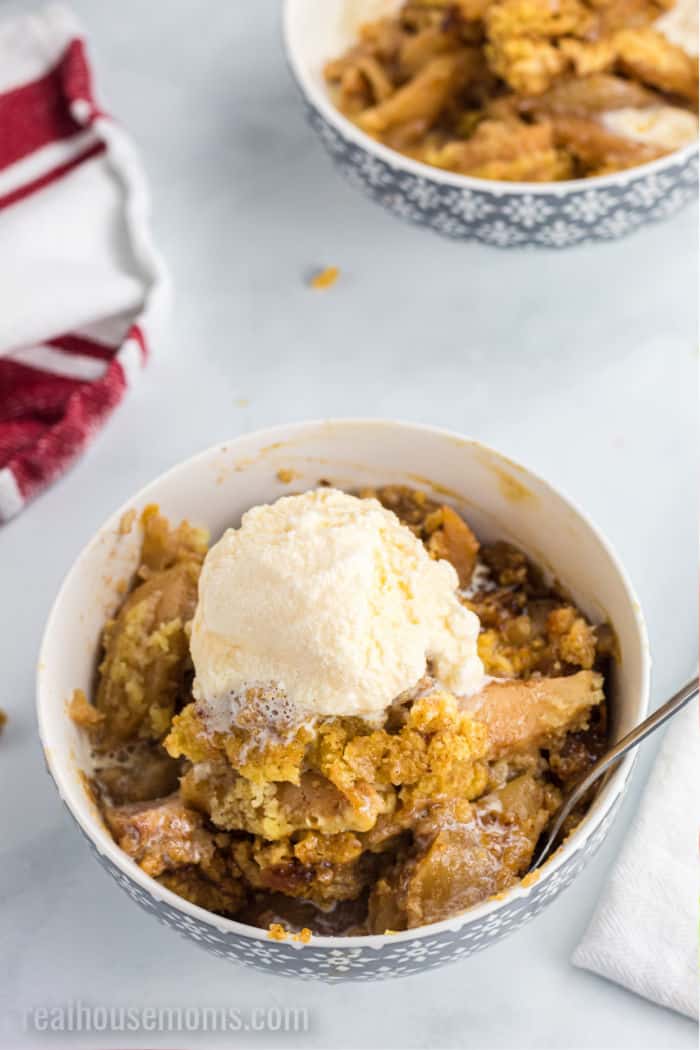 crock pot apple cobbler in bowls topped with ice cream