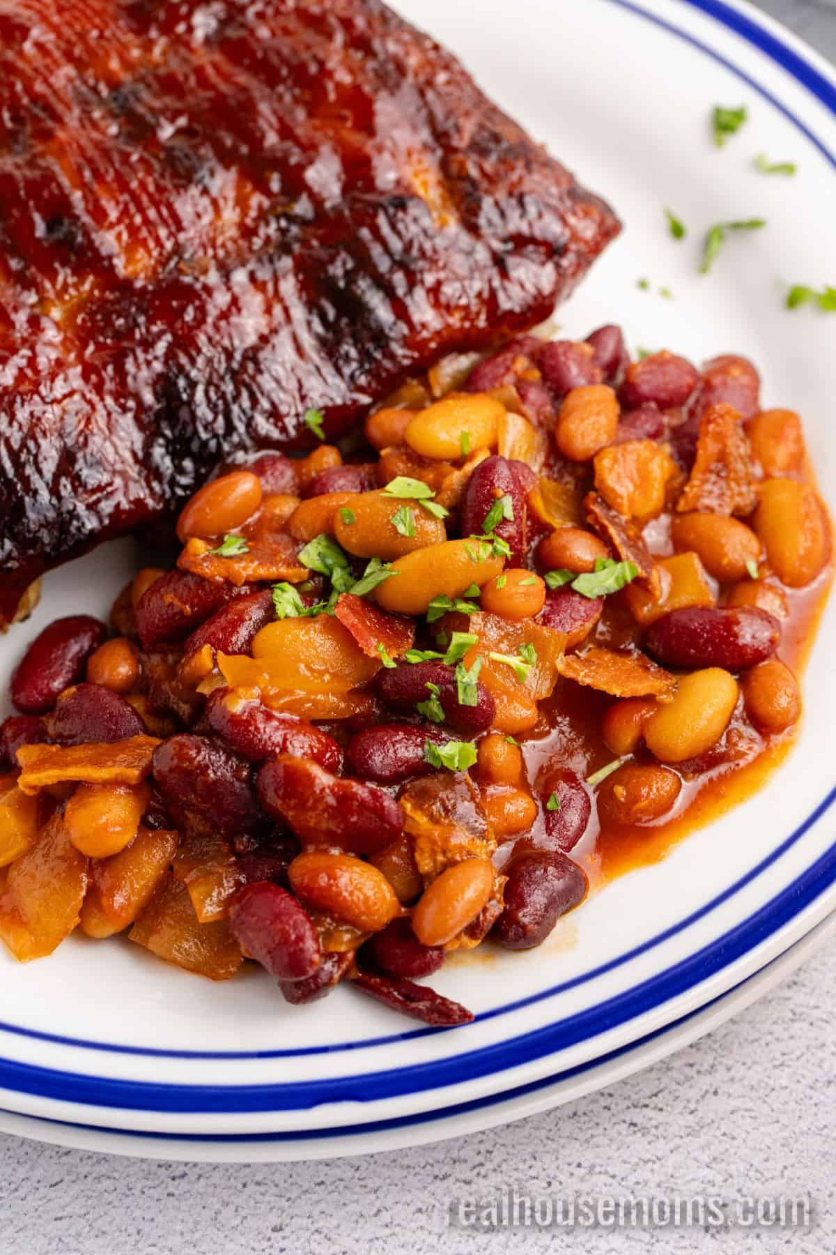 portion of crockpot baked beans on a plate with ribs