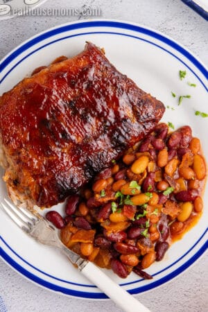 ribs and crock pot baked beans on a plate with a fork