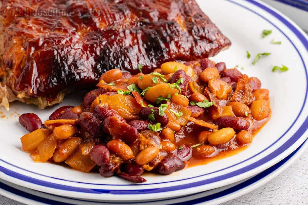 crockpot baked beans served with ribs on a dinner plate