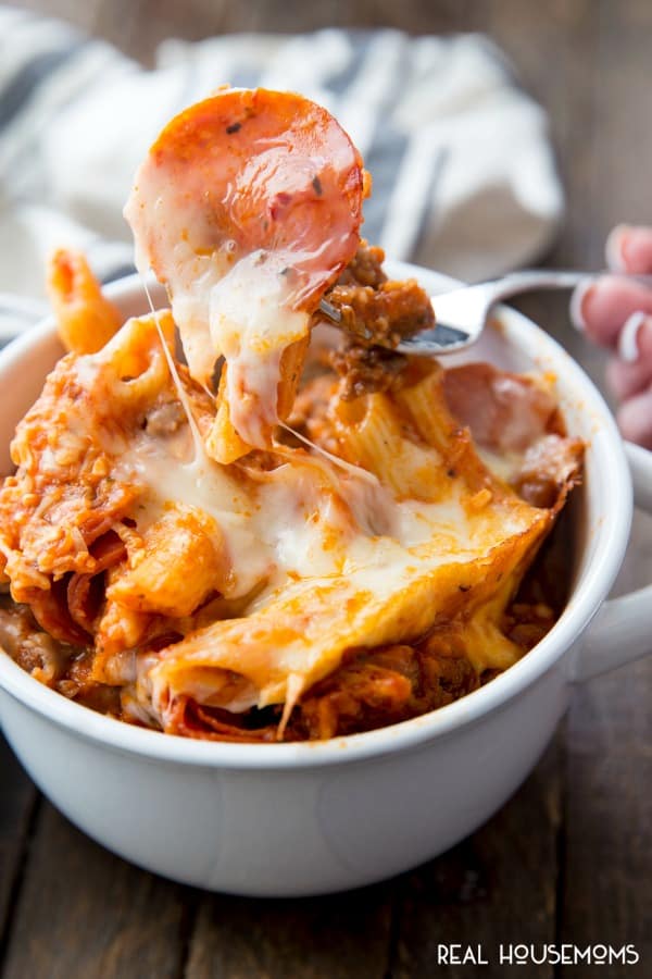 Fork digging into a bowl of Crock Pot Pizza Casserole and lifting with pepperoni and gooey cheese stretching