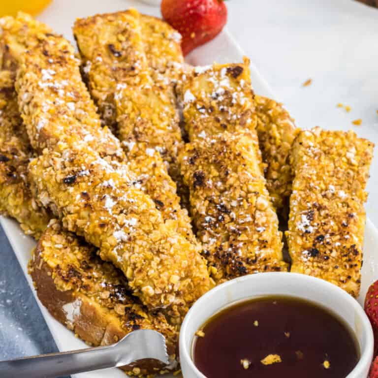 square image of french toast sticsk on a plate with a bowl of syrup