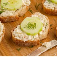 cucumber bruschetta slices on a wooden board with recipe name at the bottom
