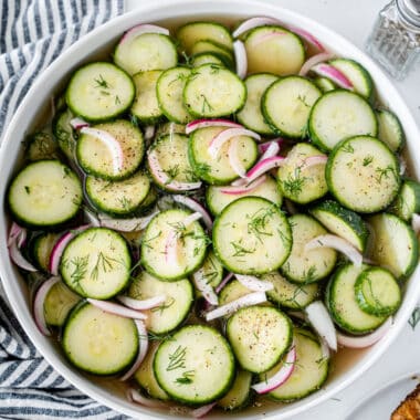 cucumber and onion salad in a serving bowl with dill sprinkled on top