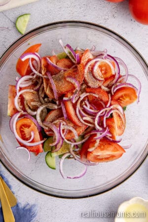 salt, pepper, olive oil, and balsamic vinegar poured over veggies in a glass bowl