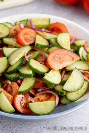 cucumber tomato salad in a serving bowl after being mixed together
