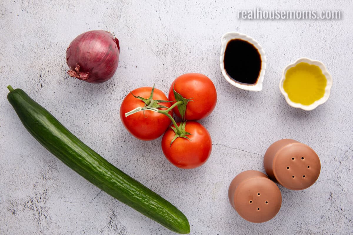 looking down at ingredients to make cucumber tomato salad on a counter