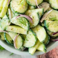 close up of cucumber yogurt dill salad in a serving bowl with recipe name at the bottom