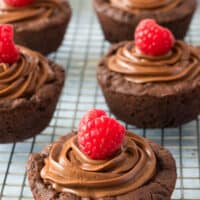picture up image of a dark chocolate cookie cups topped with a raspberry on a baking sheet with the title of the post on top in red and black lettering