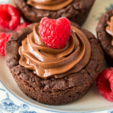 square close up image of a dark chocolate cookie cups topped with a raspberry
