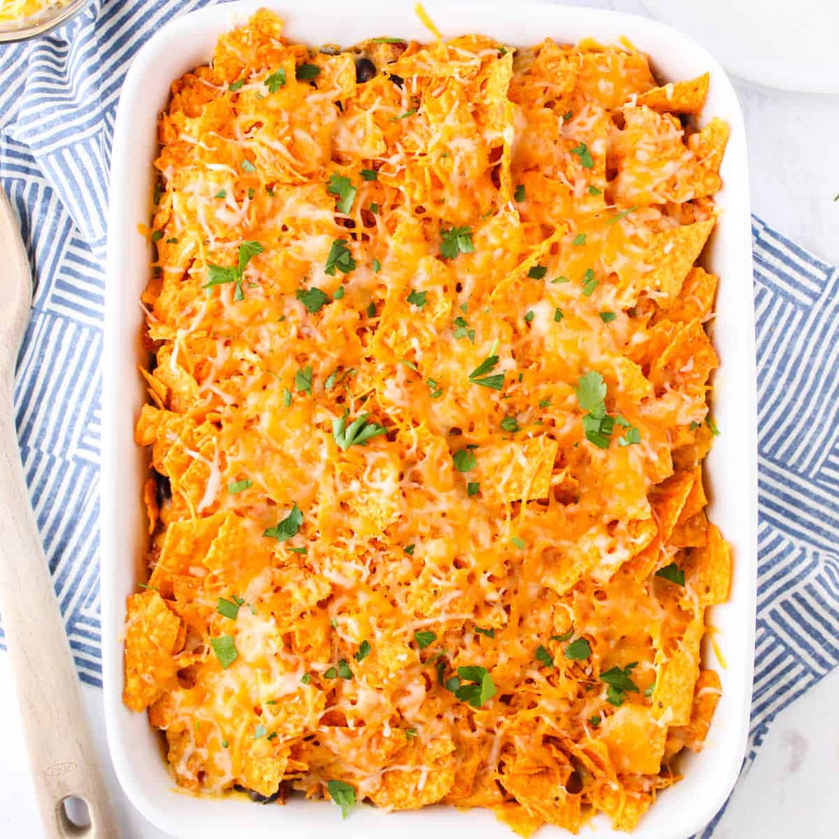square image of Dorito casserole topped with parsley in a baking dish