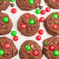 double chocolate chip M&M cookies laid out on a counter with red and green M&Ms and recipe name at the bottom