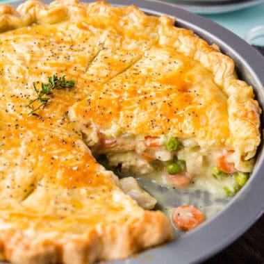 square image of double crust chicken pot pie with a slice taken out to show the filling