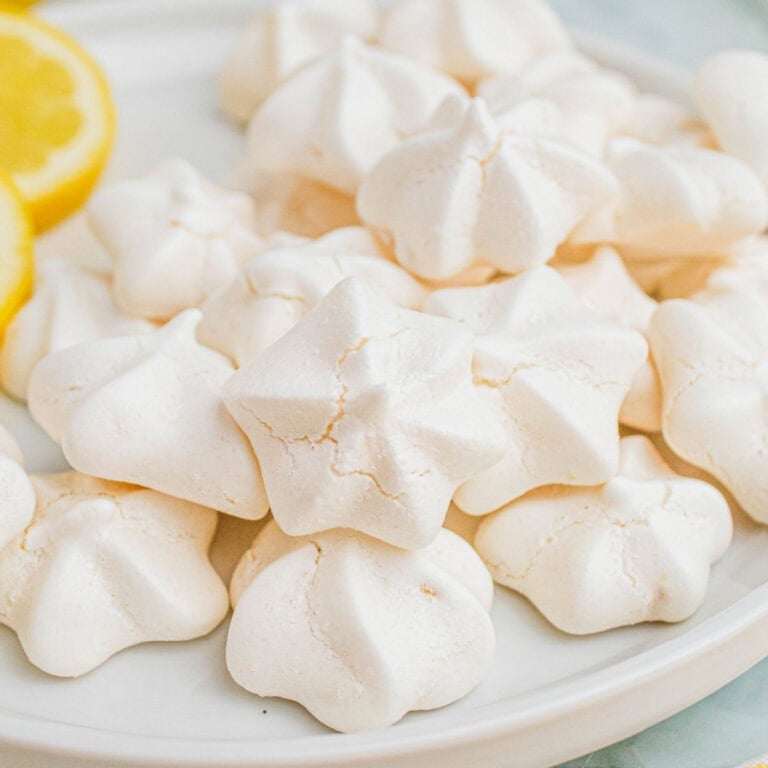 square image of double lemon meringue cookies piled on a plate