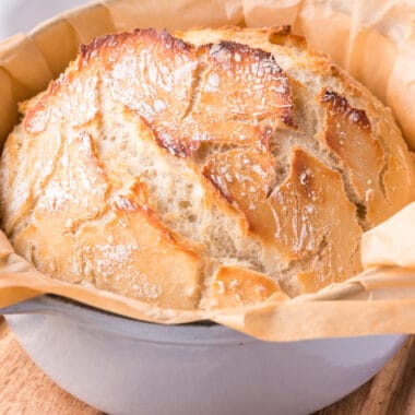 square image of dutch oven bread with parchment paper in the pot