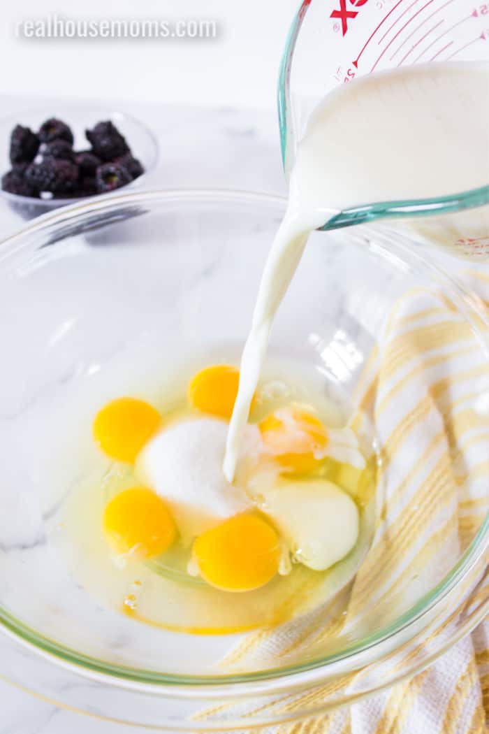 milk being poured into a mixing bowl with eggs