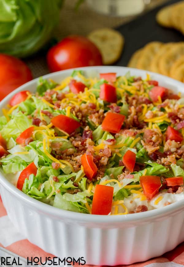 Close up photo of Easy BLT Dip topped with shredded lettuce, crumbled bacon, shredded cheddar cheese and lots of diced fresh tomaotes